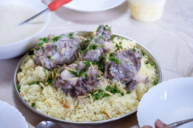 Aile sofrasında yenmeye hazır Ürdünlü mansaf et ve bademle sıcak ve taze görünüyor.