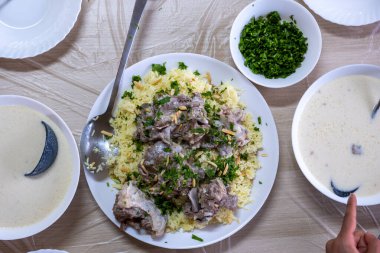 Jordanian mansaf on family table for dinner ready to be eaten looks hot and fresh with meat and almonds topping clipart