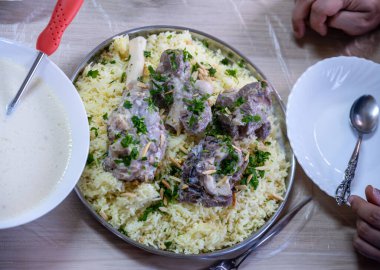 Jordanian mansaf on family table for dinner ready to be eaten looks hot and fresh with meat and almonds topping clipart