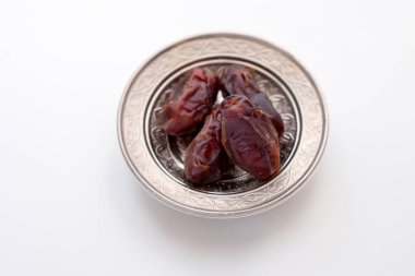 Gelenek ve işçiliği kucaklayan, güzel oyulmuş bir teneke kâse, karmaşık İslami süslemelerle süslenmiş, sulu hurma dolu, Ramazan ve Kurban Bayramı 'nın bereketini simgeleyen