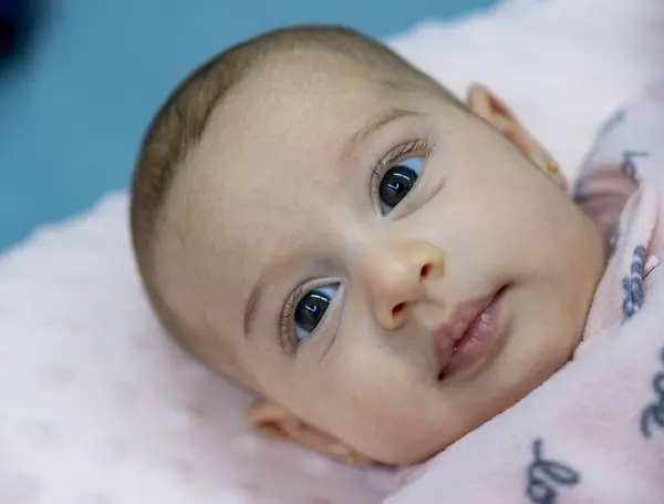 stock image portrait for 3 month 6 kilos baby while lying on his back looking at the camera with no facial expression