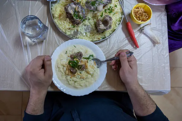 stock image male hands with mansaf from a point of view while preparing his plate with meat,rice jameed ,nuts and parsley during iftar in ramadan