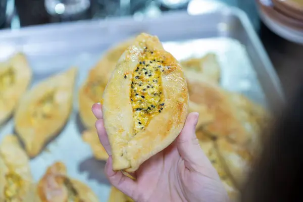 stock image Old man hands holding aluminum plate full of white cheese stuffed pastries and putting it in old oven