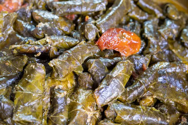 Pirinçle doldurulmuş üzüm yapraklarıyla dolu paslanmaz çelik tencere ve aroması için biraz domates.