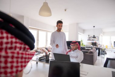 Görevdeyken projeyi bitirmek için toplantı masasında dizüstü bilgisayar kullanan Arapça