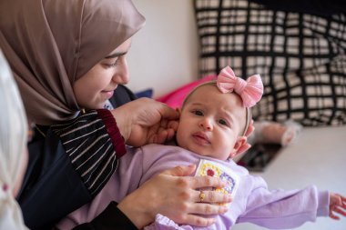 Anne kucağında çocuk kameraya bakıyor bebeğine aşık oluyor güzel giysiler içinde bayramı kutluyor.