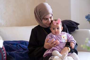 Anne kucağında çocuk kameraya bakıyor bebeğine aşık oluyor güzel giysiler içinde bayramı kutluyor.