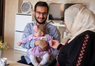 Baba kucağında yeni doğmuş bebek gülümseyen ve kameraya bakan heyecanlı ve sevgi dolu