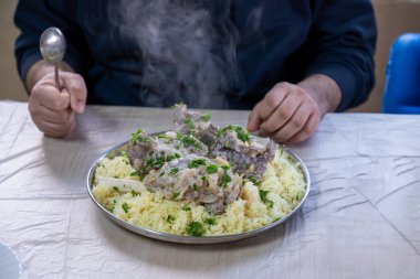 male hands with mansaf from a point of view while preparing his plate with meat,rice jameed ,nuts and parsley during iftar in ramadan clipart