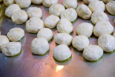 Dough balls on metal tray with olive oil to make sure it is not sticking and can be shaped later to be used and stuffed clipart