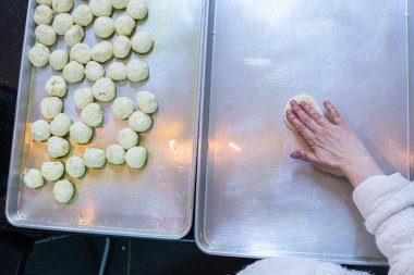 Female hands flattening dough balls and shaping it in circles to be stuffed later, dough hand made clipart