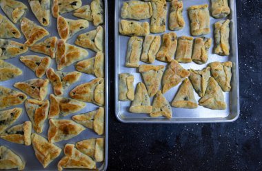 Siyah mermer arka planda pişmiş hamur işleri servis edilmeye hazır ve yemek masasındaki alüminyum tepsiden kaselere ya da okul çocuklarının sırt çantasına taşınmaya hazır.