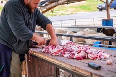 Eti elinde tutan bir adam taze ve lezzetli eti satışa sunuyor.