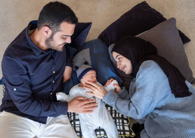 Arabic Muslim parents share a tender moment with their newborn daughter, radiating love and joy in their home. clipart