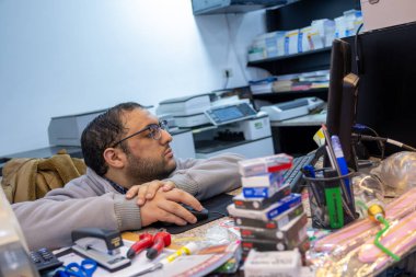 Masasında matbaa hizmetleri için arka planda yazıcılar olan bir kitapçı.