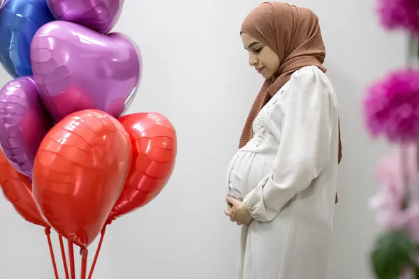 stock image pregnant Arabic muslim female on isolated white background touching her tummy showing her body shape during 9th month of pregnancy