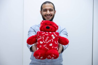 Elinde kırmızı kalpli bir hediye kutusu olan bir adam.