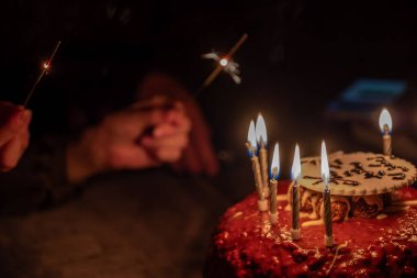 Bir el, kutlama için pastadaki doğum günü fişeklerini yakar.