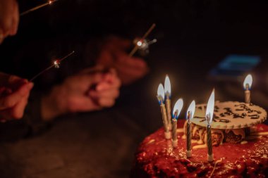 Bir el, kutlama için pastadaki doğum günü fişeklerini yakar.