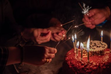 Bir el, kutlama için pastadaki doğum günü fişeklerini yakar.
