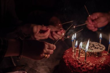 Bir el, kutlama için pastadaki doğum günü fişeklerini yakar.