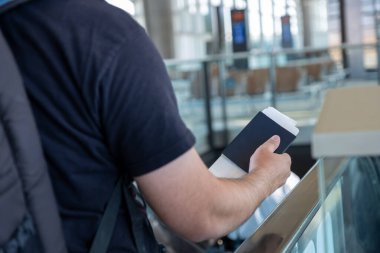 Pasaportunu havaalanında tutan genç Arap erkek arka planda uçakla yeni bir maceraya hazır.