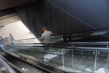 İnsanlar seyahatleri sırasında yürüyen merdiven kullanıyorlar.