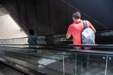 İnsanlar seyahatleri sırasında yürüyen merdiven kullanıyorlar.