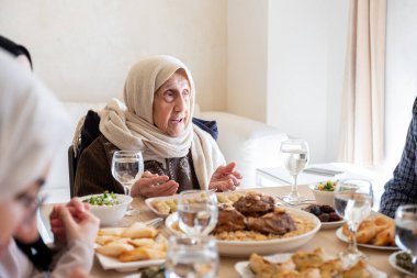 Modern oturma odasında, çok nesilli üyelerle birlikte yemek yiyorlar.