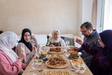 Modern oturma odasında, çok nesilli üyelerle birlikte yemek yiyorlar.