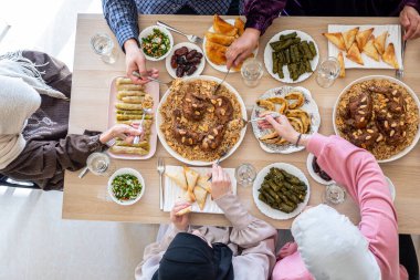 Top view for Arabian family having dinner together on wooden table with father,mother,grandfather,grandmother and son clipart