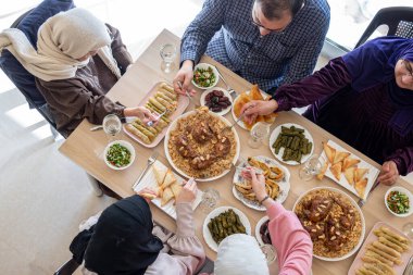 Arap ailesi için en iyi manzara ahşap masada baba, anne, büyükbaba, büyükanne ve oğulla birlikte yemek yemek.