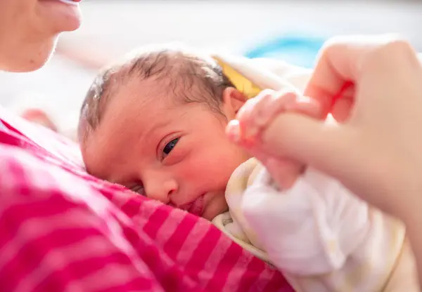 stock image mother cuddling her newborn with smile on their faces and adorable look on baby face