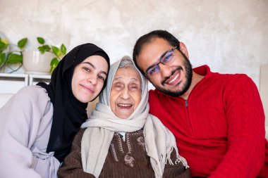 Anne, baba ve büyükanne modern oturma odasında mutlu bir aile olarak.