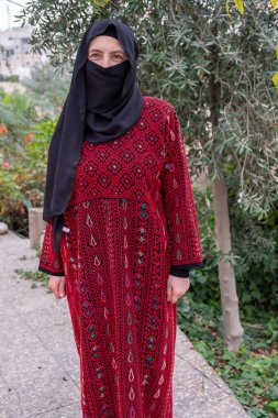 Mülteci kampında zeytin ağacının arkasında geleneksel giysiler giyen kadın portresi