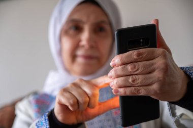 Filistin 'de geleneksel giysiler giyen bir kadın Filistin' deki akrabalarıyla kanepede telefon görüşmesi yapıyor.