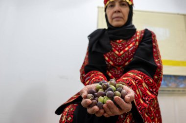Filistinli kadın elinde zeytin yumağı tutuyor.