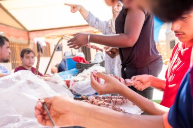 Çok ırklı insanlar piknikte ve kebap ve barbekü hazırlarken birbirlerine yardım ediyorlar.