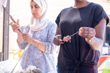 Çok ırklı insanlar piknikte ve kebap ve barbekü hazırlarken birbirlerine yardım ediyorlar.