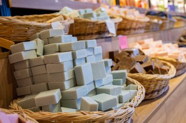 Bir mağazada el yapımı yeşil sabun dolu sepet ahşap arka planda vücut bakım ürünlerinden oluşur.