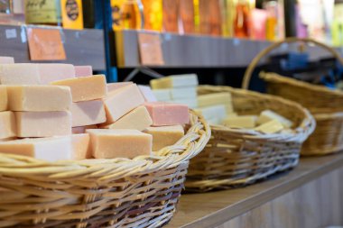 Bir mağazada el yapımı çiçek sabunu dolu el yapımı sepet ahşap arka planda vücut bakım ürünlerinden oluşur.