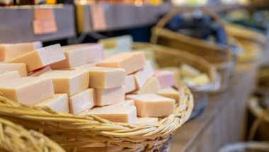 Bir mağazada el yapımı çiçek sabunu dolu el yapımı sepet ahşap arka planda vücut bakım ürünlerinden oluşur.