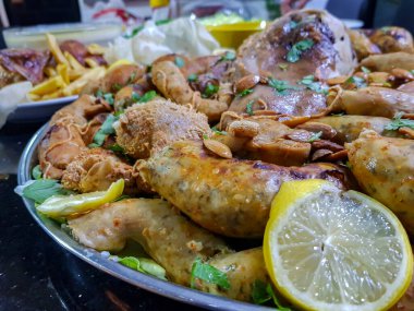 Üst görünüm işkembe, boşluklar, limonlu bacaklar ve siyah arka planda bitkiler yenmeye hazır.