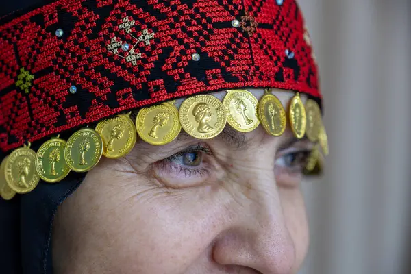 stock image A Palestinian woman head dress in red and black with golden accessories