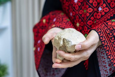 Filistinli bir kadın elinde, işgale karşı koyabilecek tek silahı temsil eden bir taş tutuyor.