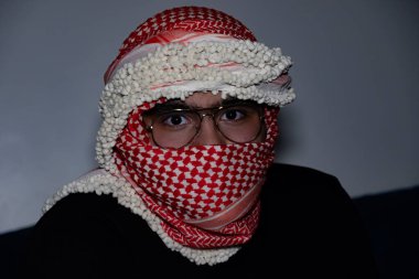 Koyu arka planda kırmızı keffiyeh giyen Pearl 'ün portresi. Şiddet ve işgale karşı olduğu için gözlerinde öfke ifadesi var.