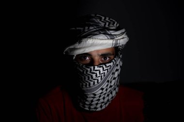 Siyah arka planda beyaz keffiyeh giyen Pearl 'ün portresi. Şiddet ve işgale karşı olduğu için gözlerinde öfke ifadesi var.