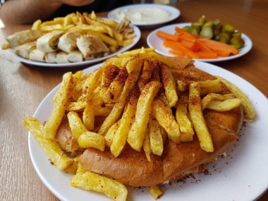 Shawarma tabağı ahşap masada servis ediliyor. Yakın çekim ve üst manzara. Ayrıca sarımsak kabının yanında patates kızartması da var.