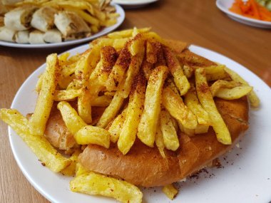 Shawarma tabağı ahşap masada servis ediliyor. Yakın çekim ve üst manzara. Ayrıca sarımsak kabının yanında patates kızartması da var.