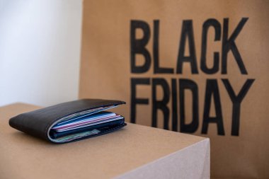 Önünde cüzdan olan siyah cuma alışveriş çantası.